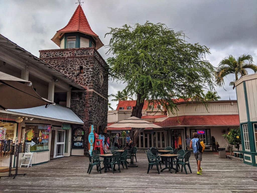 dining tables and stone tower and storefronts in Kona Village Shopping Center on Ali'i Drive on wooden boardwalk