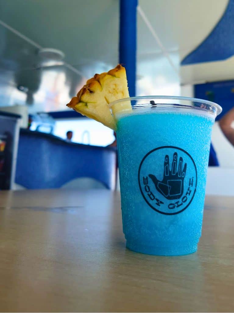 Blue Hawaiian cocktail with pineapple wedge on boat table