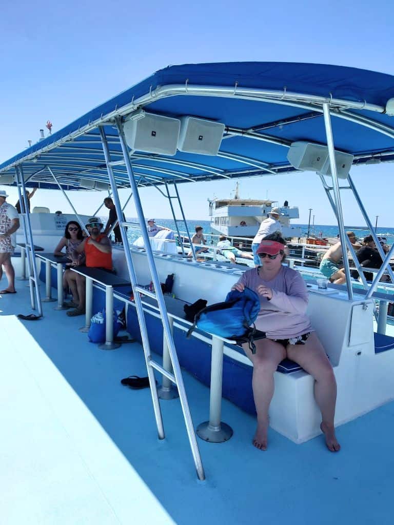 top deck of body glove, view of the middle of the boat seating with benches and bar tables and shade awning