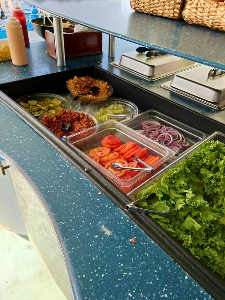 Self-serve burger bar with all the burger fixings like lettuce, tomatoes, onions, pickles, and more