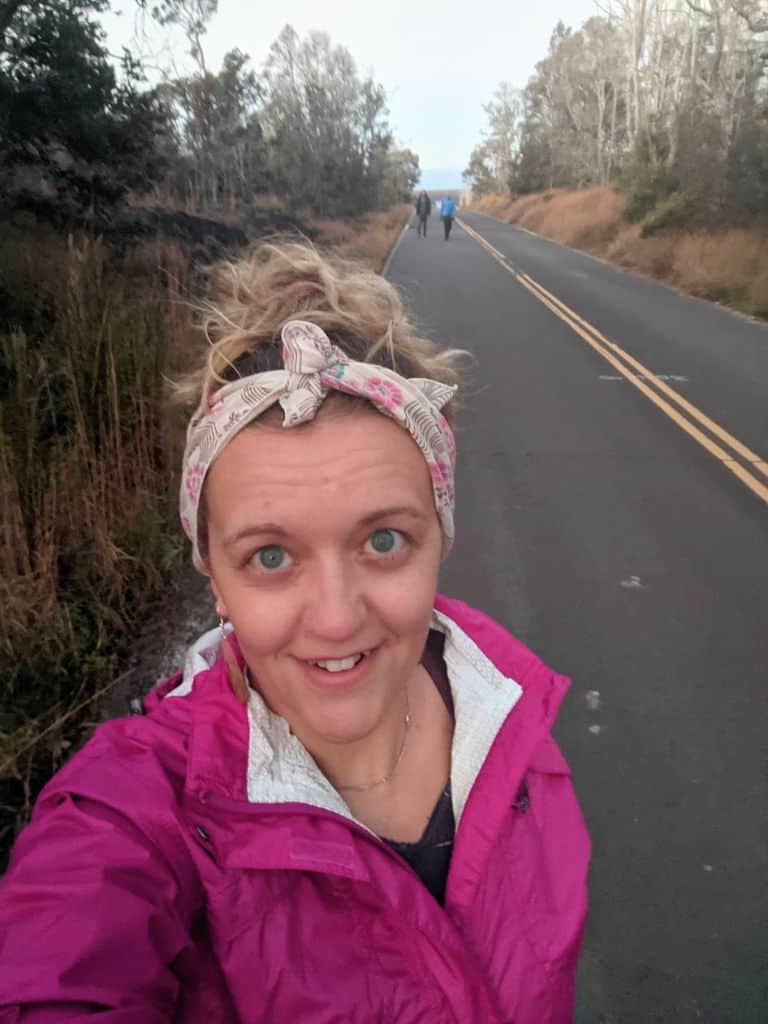 selfie of me wearing a pink rain jacket and bandana headband walking Old Crater Rim Drive Trail, which is on a now closed paved road