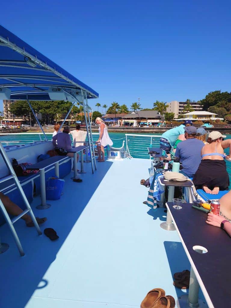 Upper deck of body glove boat with benches and bar tables. kona town in background