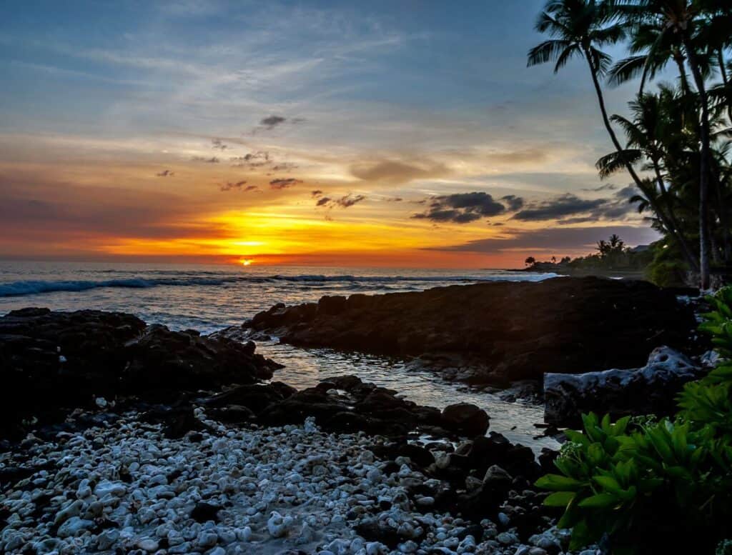 Holoholokai Beach with white coral and black lava rocks instead of sand at sunset
