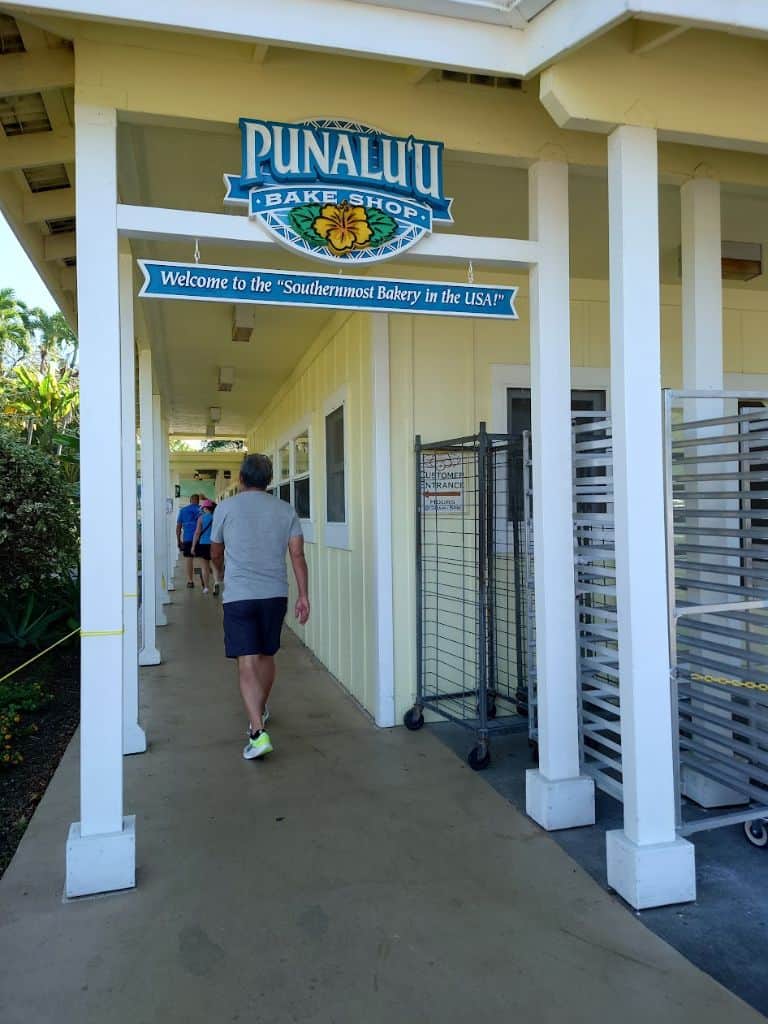people walking down the Entrance hallway to Punalu'u Bake Shop with sign that says "Welcome to the Southernmost Bakery in the USA!"