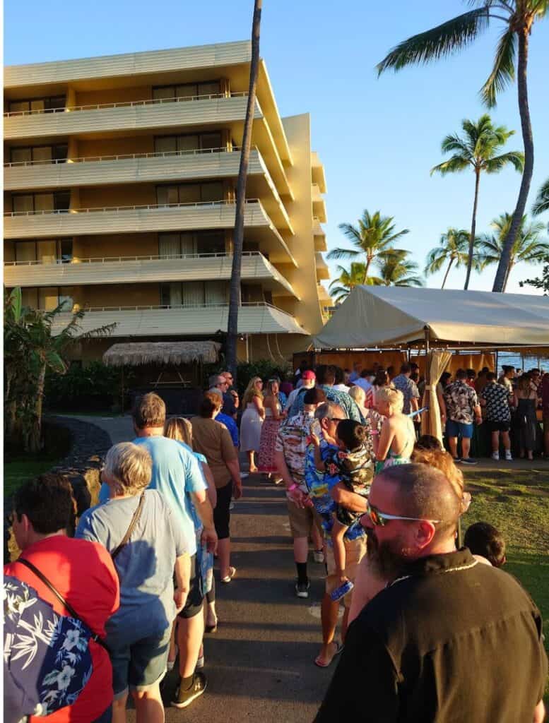 Two lines of people outside the buffet tent with royal kona resort building in background