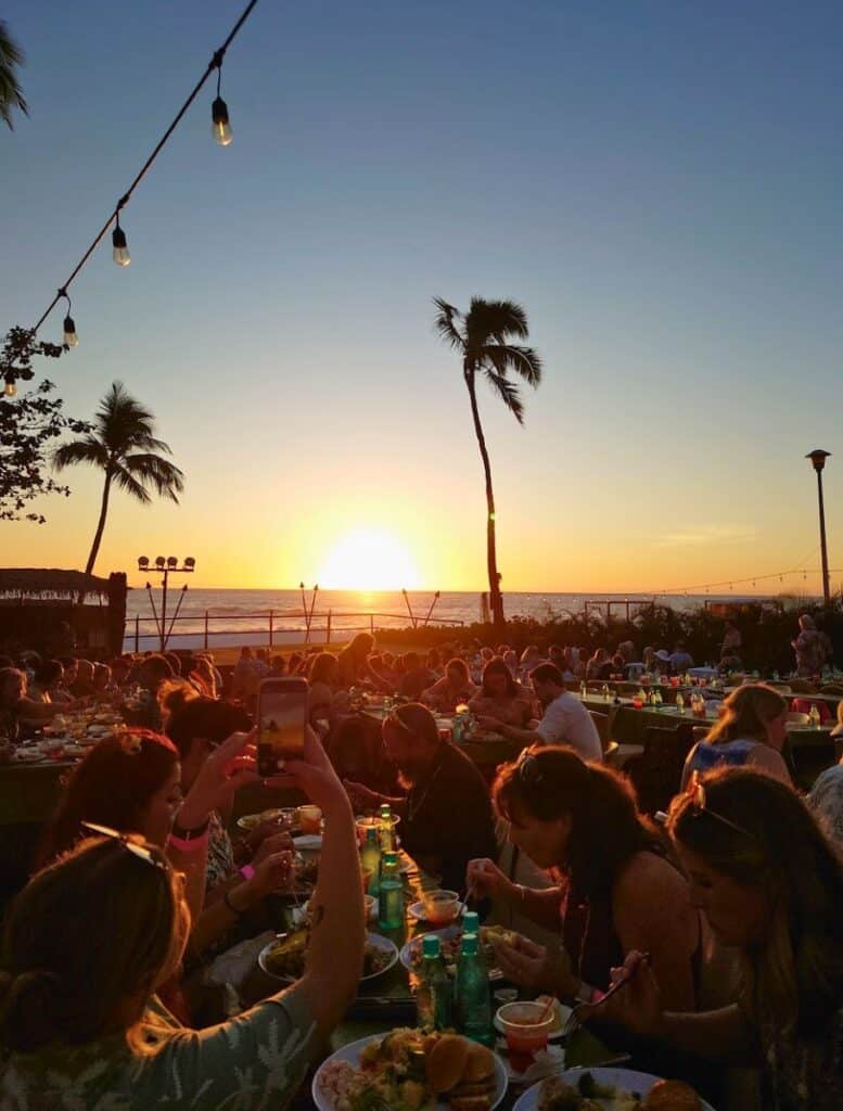 person Taking pictures of sunset with a sea of guests eating dinner at tables