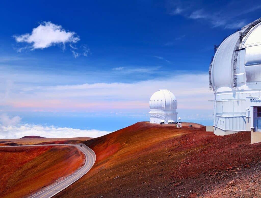 white Telescope domes at Mauna Kea summit wtih road winding below them