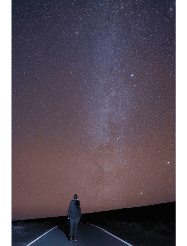 me with my back turned standing on the road looking at the milky way