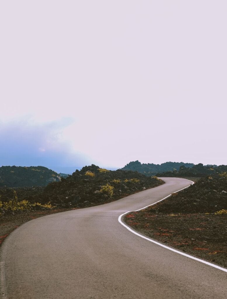 winding narrow paved road through a lava field with piles of lava rocks