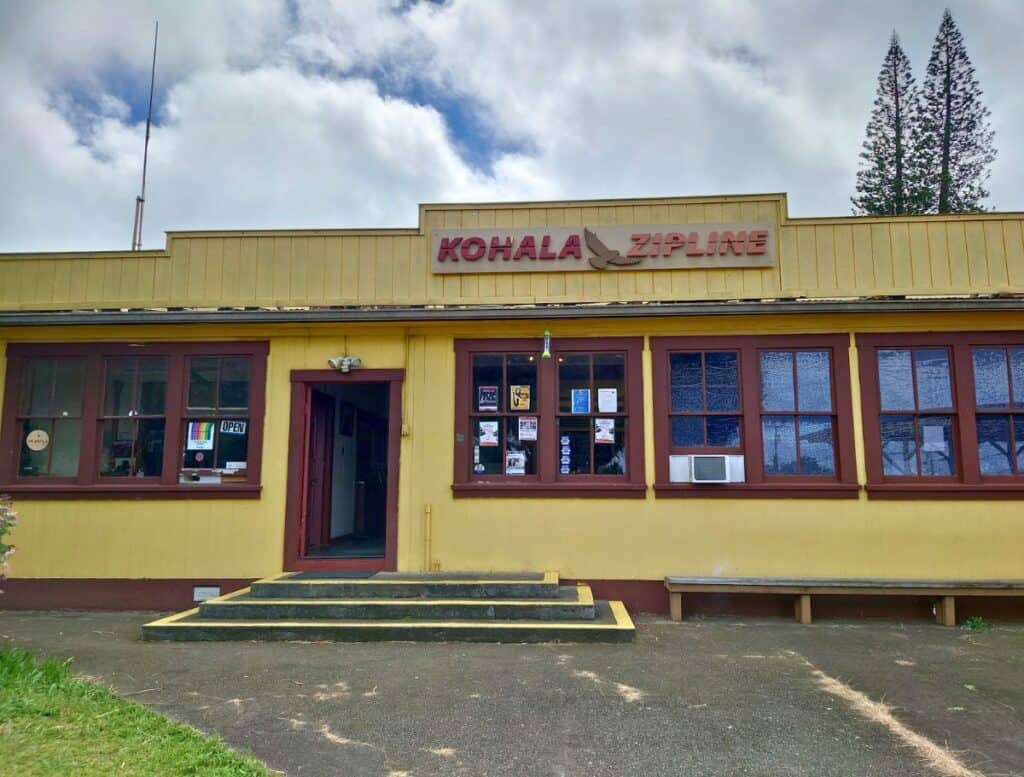 Front door of Kohala Zipline in historic yellow building with steps up to the front door