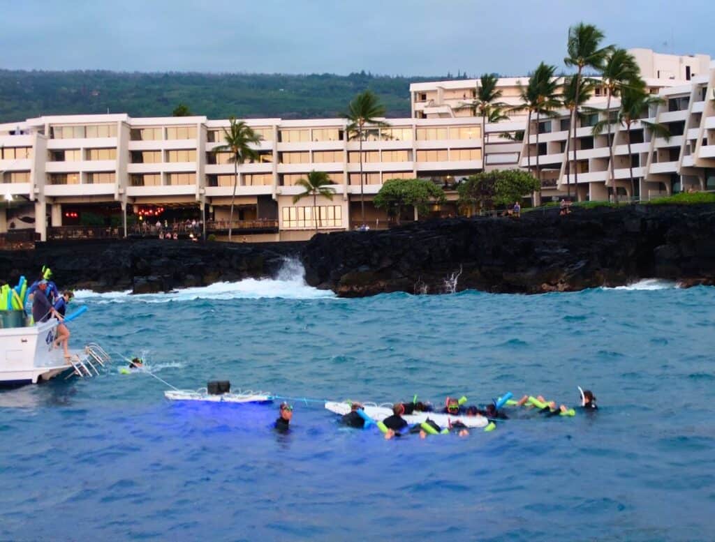 snorkel tour of people holding on to boards in front of outrigger kona resort