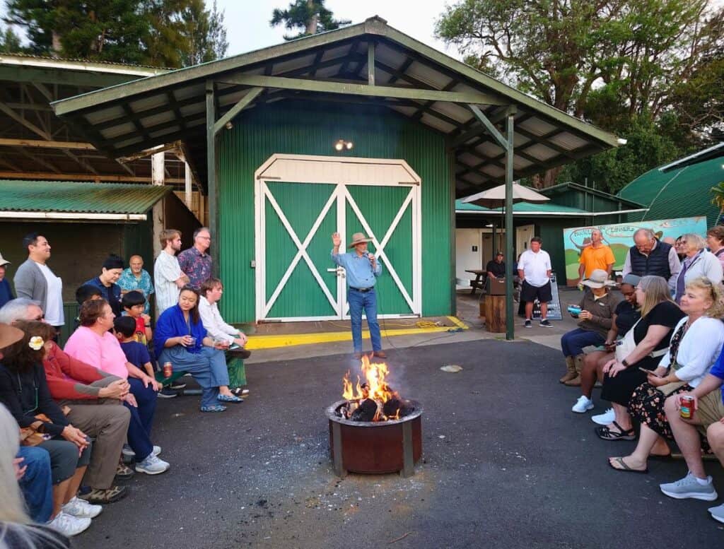 cowboy giving the history of the paniolo around the firepit with people gathered around