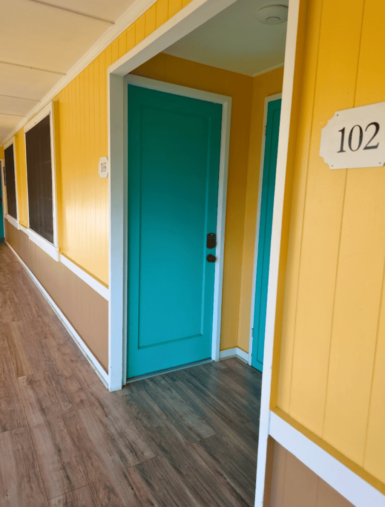 Bright teal room door with cheery yellow walls outside