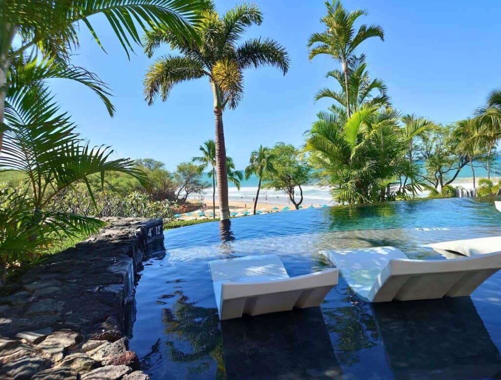 Westin Hapuna's adults-only infinity pool looking out on the beach with trees blocking some of the view