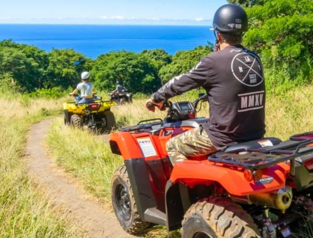 3 Polynesian ATV Tour drivers in grass field with ocean views