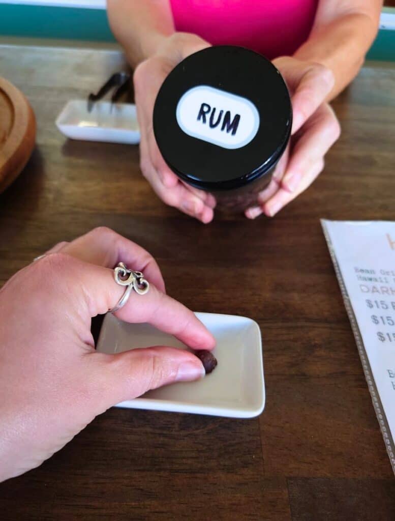 my hand Sampling rum chocolate at Honoka'a Chocolate store