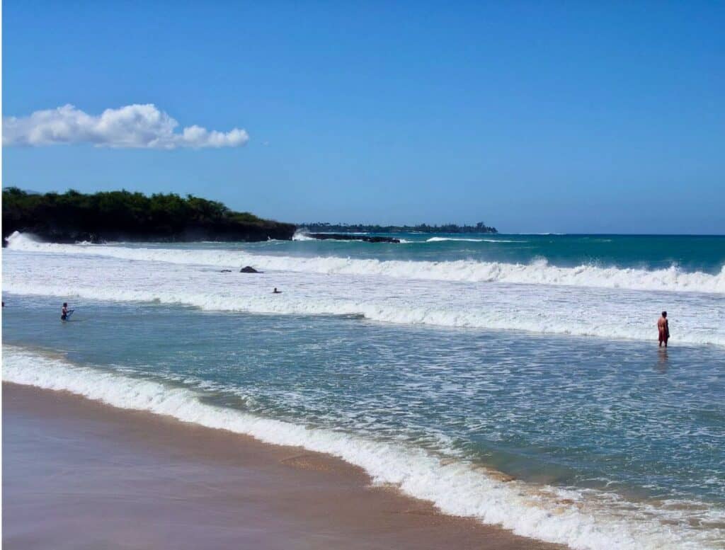 People swimming in big waves at Hapuna Beach
