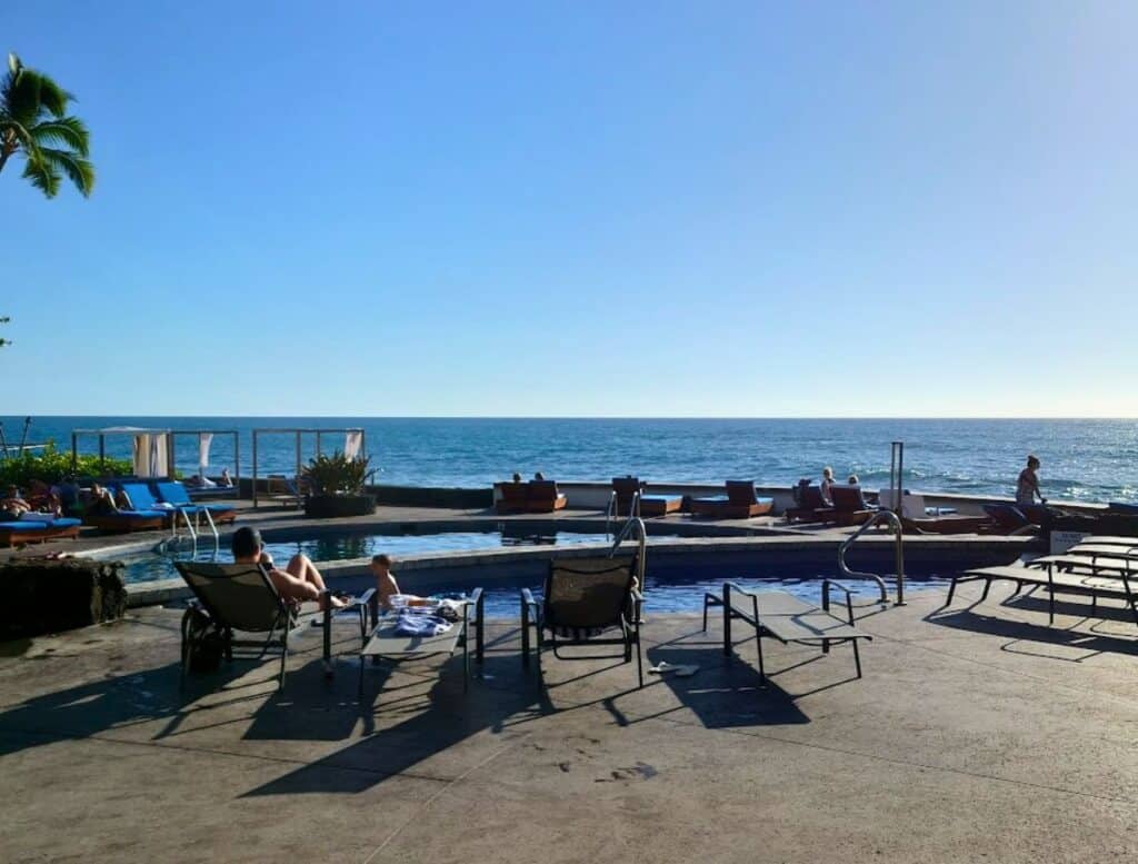 small pool with basic lounge chairs and ocean views