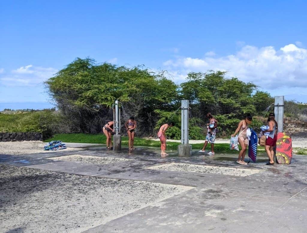 people rinsing off at outdoor Showers at Kua Bay Beach